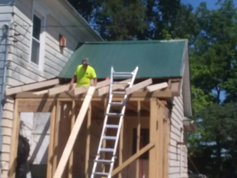 Metal roof panels and corrugated siding installation on residential framing with ladder access
