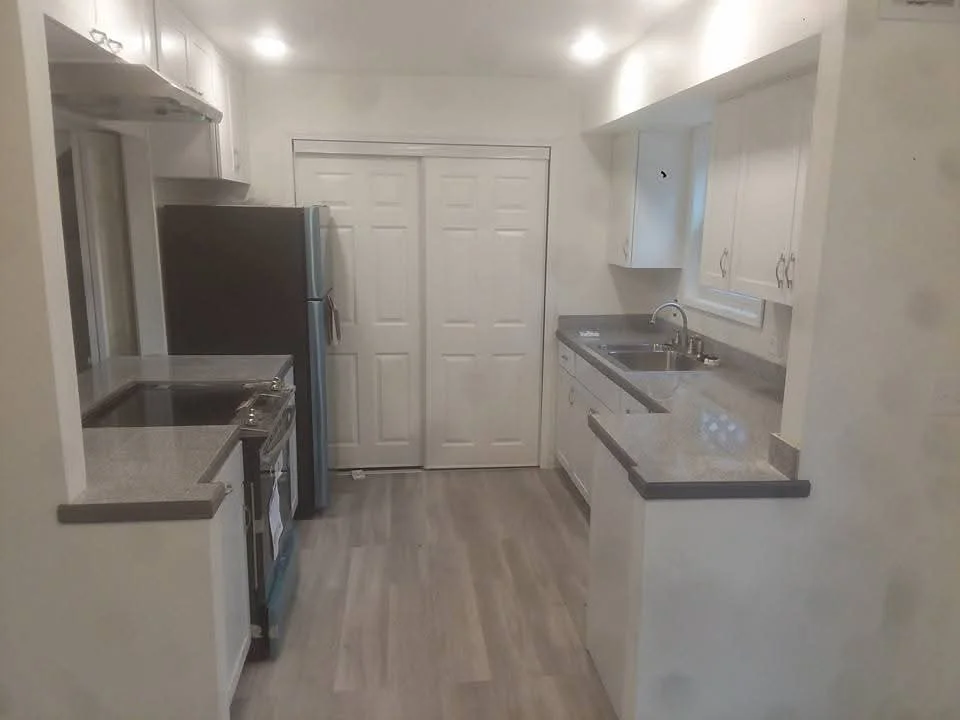 White kitchen cabinets, gray quartz counters, stainless steel appliances, vinyl plank flooring