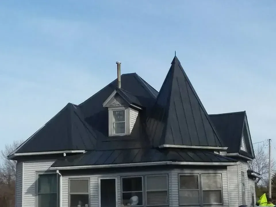 Black standing seam metal roof with chimney flashing and angled roof planes