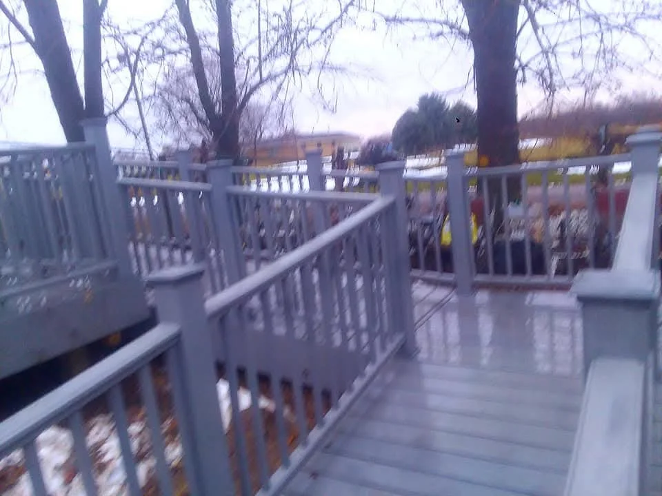 Composite deck with white vinyl railings and balusters overlooking wooded area