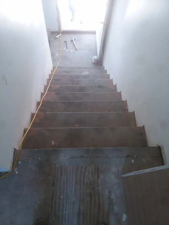 Wooden staircase framing with drywall walls and electrical conduit installation
