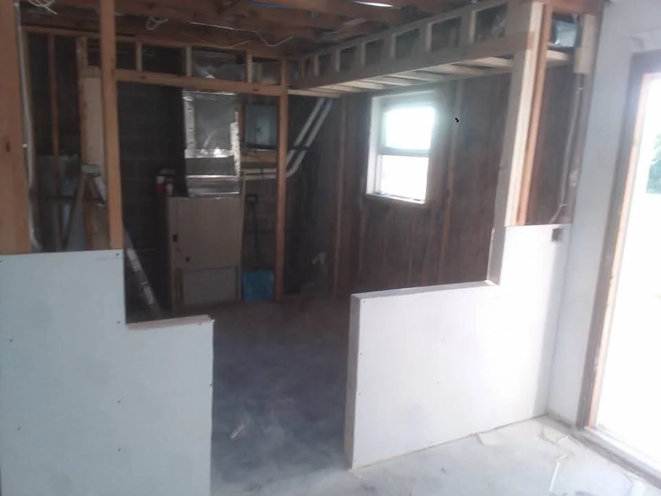 Interior framing with wood studs, drywall panels, and window installation in progress