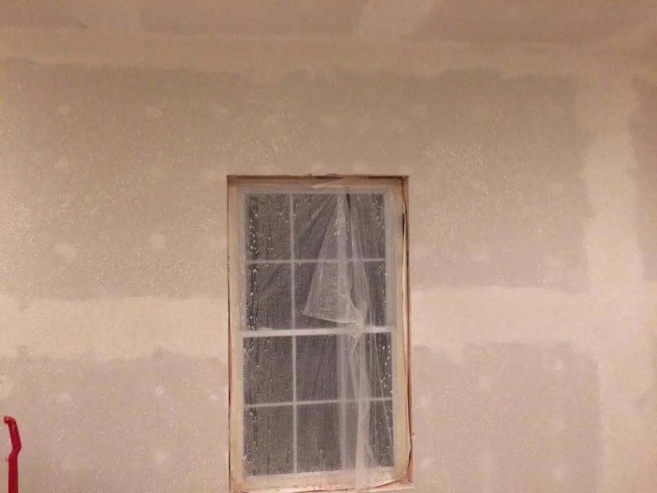 Drywall wall with taped seams and wood-framed window opening, interior construction