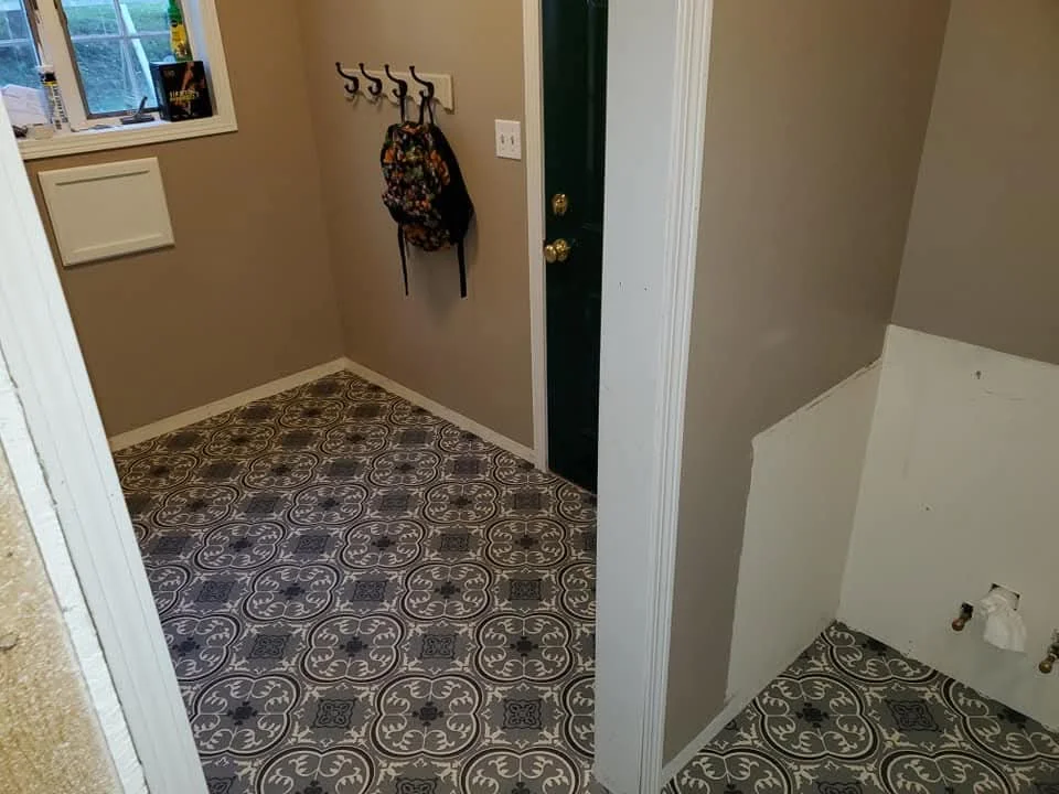 Decorative tile flooring with ornamental pattern, white trim, and neutral walls in entryway