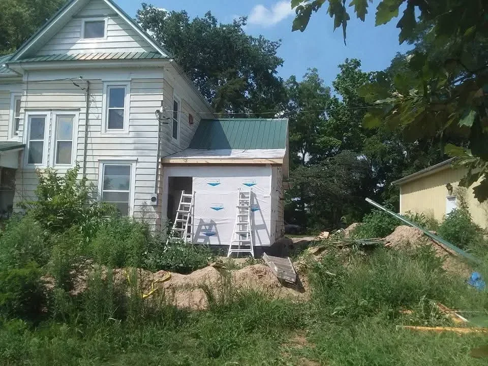 Two-story house with vertical metal siding, new windows, and metal deck railing