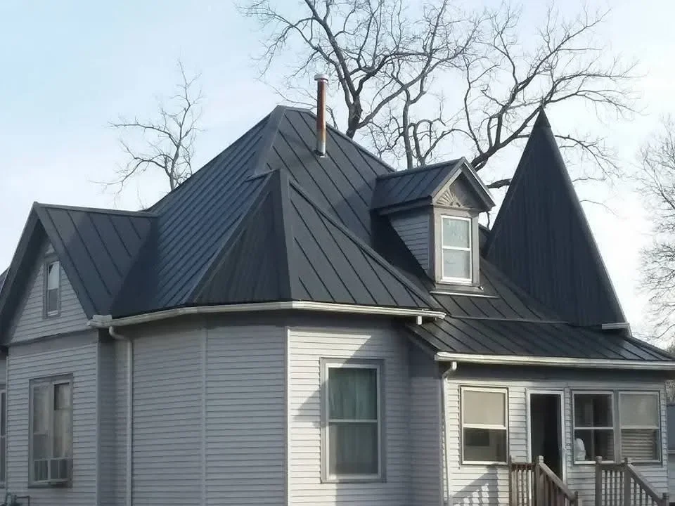 Charcoal gray standing seam metal roof with integrated gutters and flashing on residential home