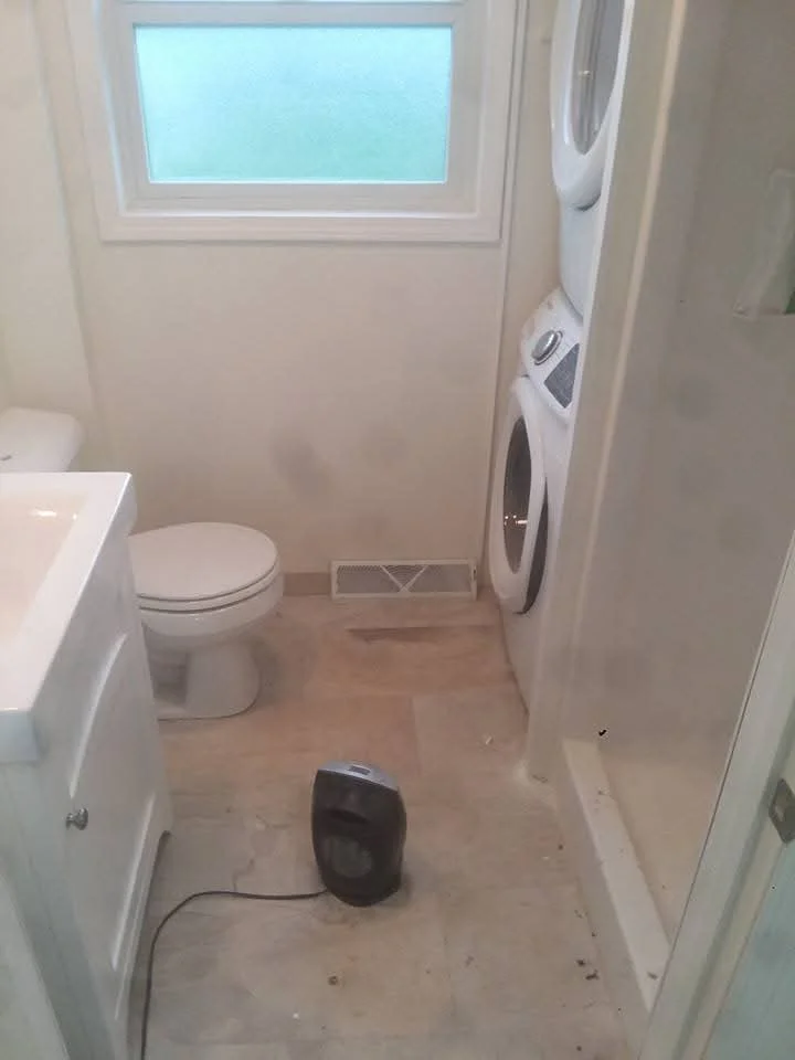 Newly renovated bathroom with white vanity, toilet, tile flooring, and washer hookup