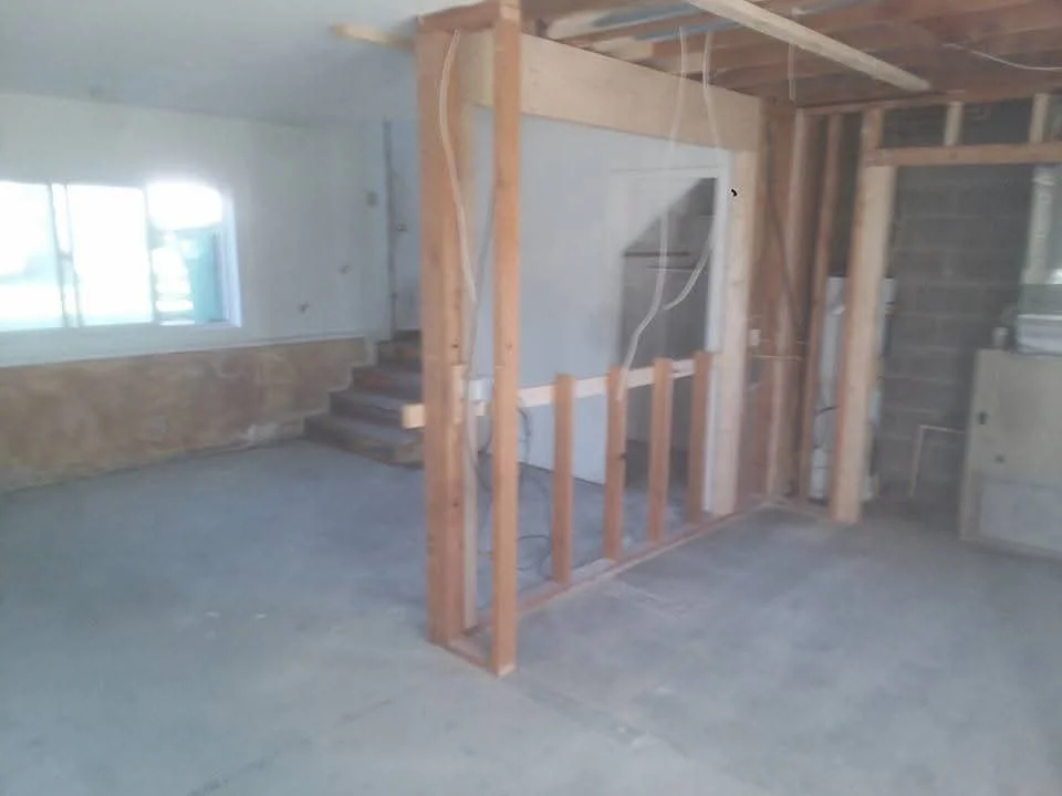 Interior framing with wooden studs and drywall installation on concrete floor