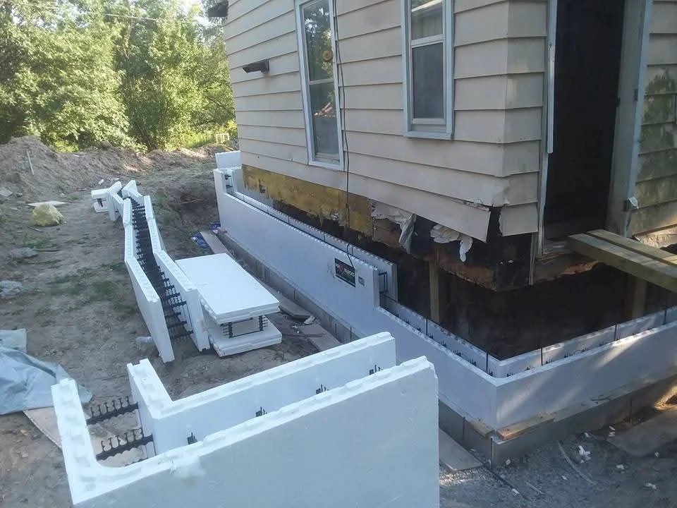 Concrete foundation posts and white vapor barrier installed under residential structure