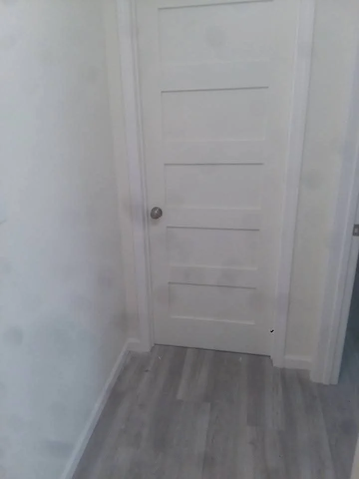 White six-panel interior door with brushed nickel hardware in hallway with laminate flooring