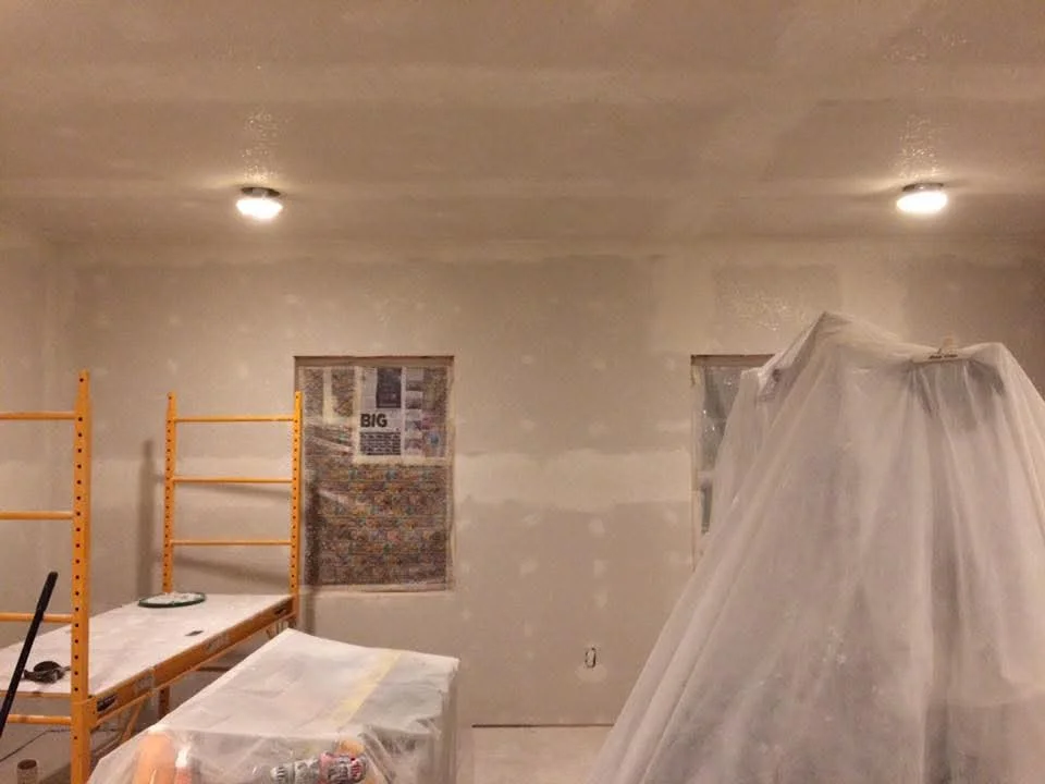 Drywall ceiling and walls with recessed lighting and protective plastic sheeting
