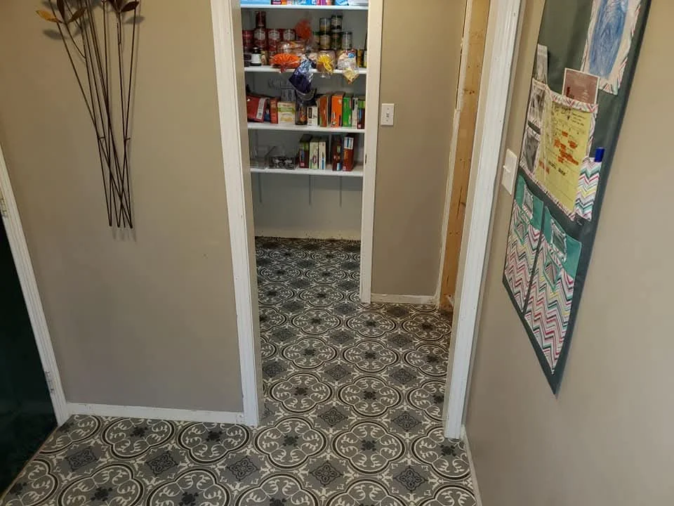 Patterned decorative tile flooring installation in kitchen and hallway with white trim