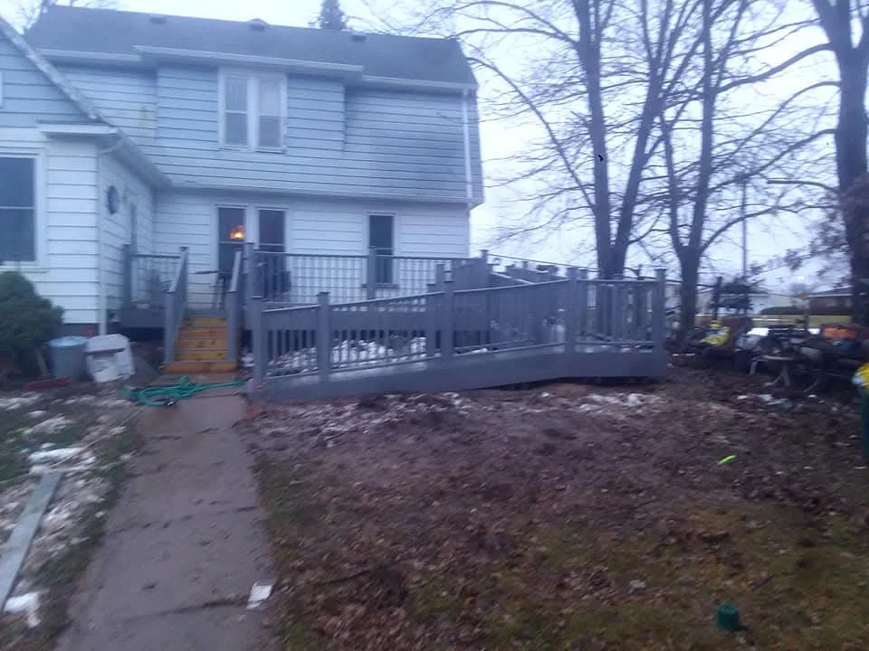 Dark composite deck with aluminum railings attached to white house exterior